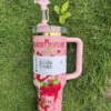 Pink tumbler with strawberry-inspired artwork Pink strawberry-inspired tumbler with bow straw topper